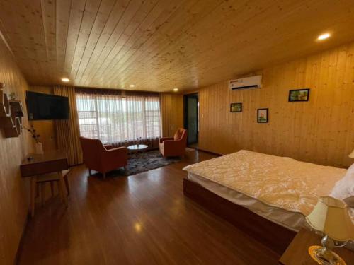 a bedroom with a bed and a living room with chairs at An Nhiên Villa in Bao Loc