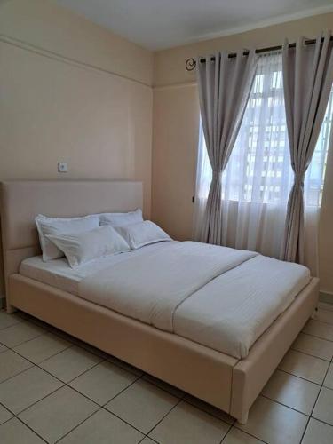 Schlafzimmer mit einem großen weißen Bett und einem Fenster in der Unterkunft Wenwa Homes South B702037774 (1 bedroom) in Nairobi