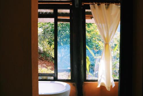 uma janela de casa de banho com uma banheira e uma cortina em Moc Chau Retreat em Mộc Châu