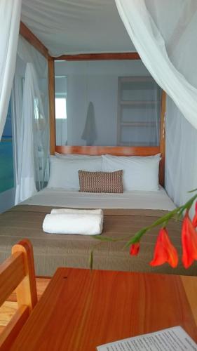 a bedroom with a large bed with red flowers at Shaquila Lodge in Fernão Veloso