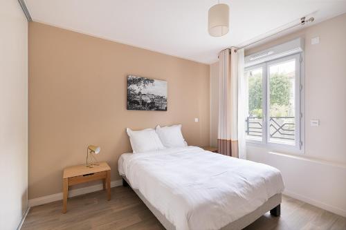 een slaapkamer met een wit bed en een raam bij Zenao Appart'hôtels Le Raincy in Le Raincy