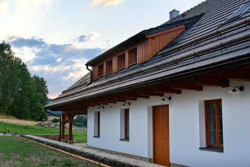 a white building with a wooden roof on a field at Chalupa Pod Šerovnou in Prachatice
