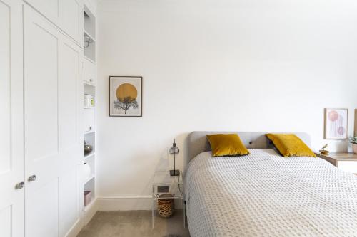 a white bedroom with a bed with yellow pillows at Hidden Gem – Luxe Clifton Apartment with Views in Bristol