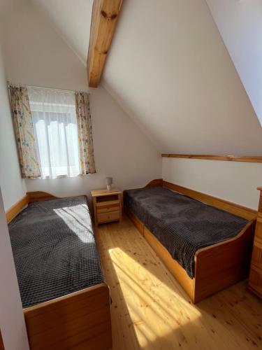 two beds in a attic bedroom with a window at Chata Sára in Snina