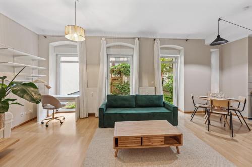 - un salon avec un canapé vert et une table dans l'établissement Arbio I 1A Rooms & Apartments Prenzlauerberg Berlin, à Berlin