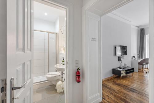 a white bathroom with a toilet and a television at Arbio I 1A Rooms & Apartments Prenzlauerberg Berlin in Berlin