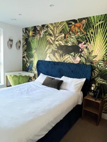 a bedroom with a blue bed with a tropical wallpaper at Stunning Riverside View Apartment, near Canary Wharf & O2 in London