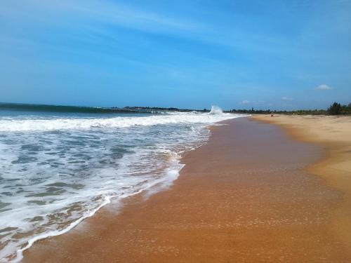 una spiaggia con l'oceano e la costa di Ganesh Gate a Pottuvil