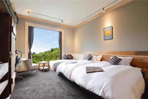 two beds in a hotel room with a large window at Shelter Garden Nikko in Nikko