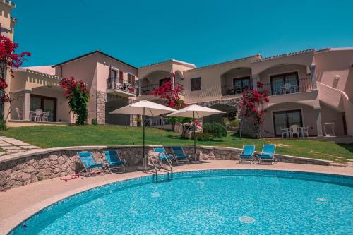 a swimming pool with chairs and umbrellas in front of a building at The Fantastic Residenza Badus two bedroom sleeps six plus child num0818 in Badesi