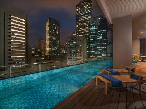 a swimming pool on the roof of a building with a city skyline at Citadines Salcedo Makati in Manila