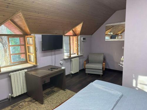 een kamer met een bureau, een tv en een stoel bij Friends Hostel in Chişinău