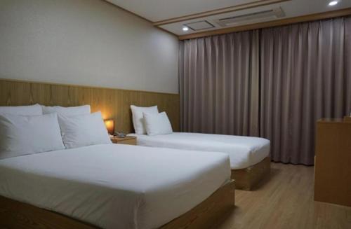 a hotel room with two beds and a window at Soldongsan Stay in Seogwipo
