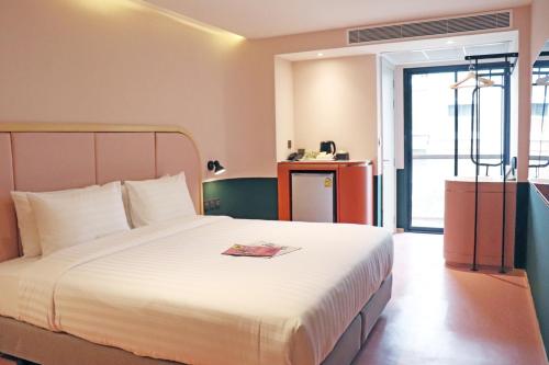 a hotel room with a bed with a book on it at The Quarter Ratchathewi by UHG in Bangkok