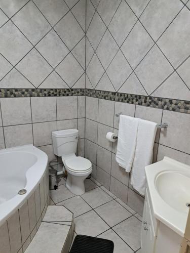 a white bathroom with a toilet and a sink at Partridge Place in Kempton Park