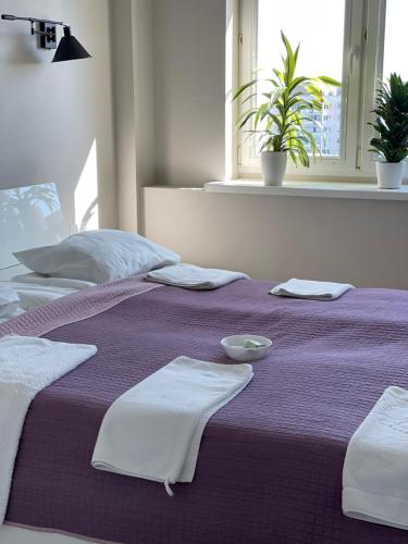 a purple bed with towels and a bowl on it at Dziesiąte Piętro in Poznań