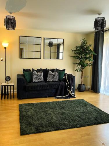 a living room with a black couch and a rug at Majestic House - Milton Keynes Serviced Accommodation in Milton Keynes