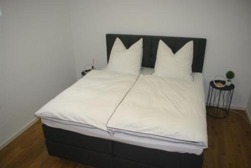 1 cama grande con sábanas y almohadas blancas en Ferienwohnung Felsterrasse, en Wasserliesch