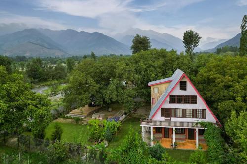 an aerial view of a house with mountains in the background at StayVista at Lavender Haze - 3BR Cottage in Pahalgām