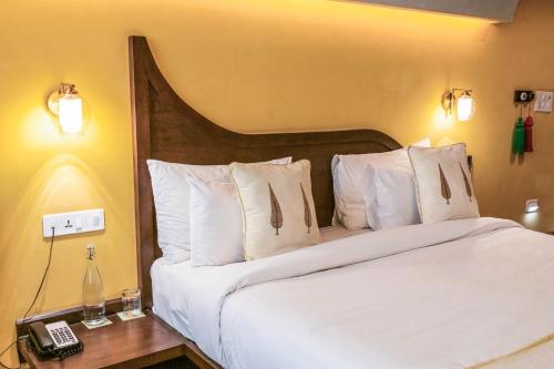 a bed with white pillows and a phone on a table at Ekaa Villa near Taj Mahal in Agra