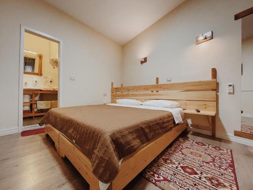 a bedroom with a large bed with a wooden headboard at At Pikotiko's - Korca City Rooms for Rent in Korçë