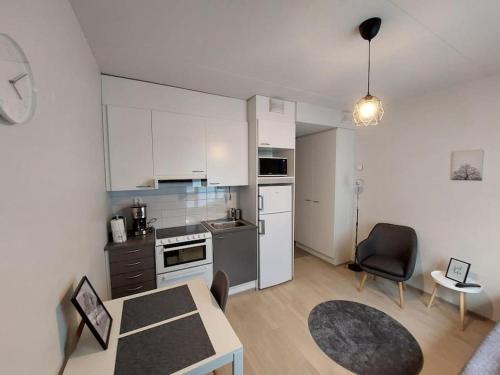 une cuisine avec des placards blancs, une table et une chaise dans l'établissement Kotimaailma Apartments Vapaudenkatu 48-50 B3, à Jyväskylä