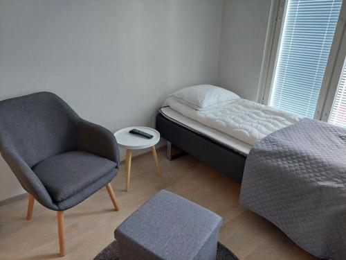 een kleine slaapkamer met een bed en een stoel bij Kotimaailma Apartments Vapaudenkatu 48-50 B3 in Jyväskylä