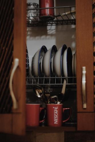 a cupboard with plates and mugs in it at At Pikotiko's - Korca City Rooms for Rent in Korçë