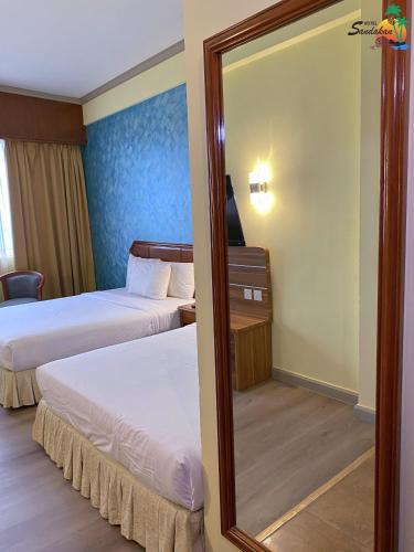 a hotel room with two beds and a mirror at Hotel Sandakan in Sandakan
