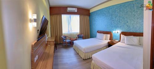 a hotel room with two beds and a television at Hotel Sandakan in Sandakan