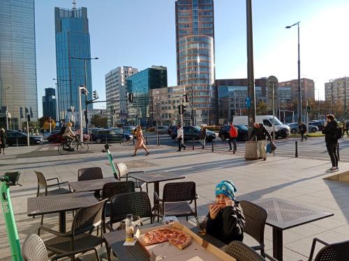 a woman sitting at a table with a slice of pizza at 918A Warsaw Center Free Parking TAMARS in Warsaw