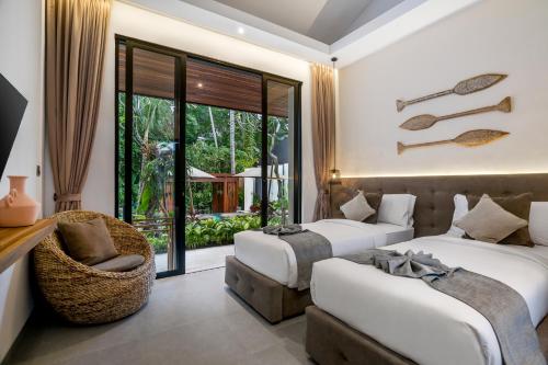 une chambre d'hôtel avec deux lits et une chaise dans l'établissement Sarang Cocoon Villa Ubud by BaliSuperHost, à Ubud