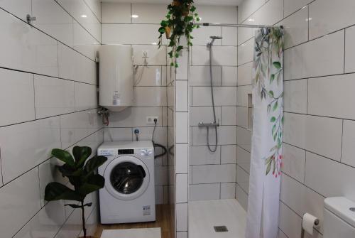 a white tiled bathroom with a washing machine at Casa El Cuarto con preciosas vistas en Candelaria in Candelaria