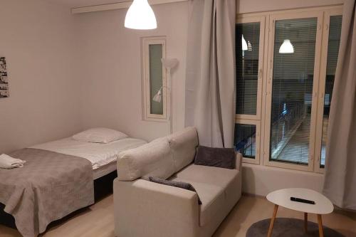 a bedroom with a bed and a couch and a chair at Top location studio in town right next to the train station and free parking Kotimaailma Apartments in Jyväskylä