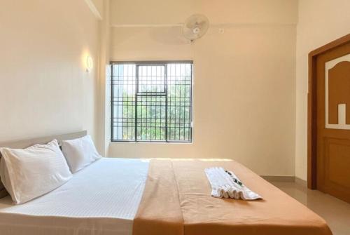 a bedroom with a large white bed with a window at Dazzle Mount Resort in Kalpetta
