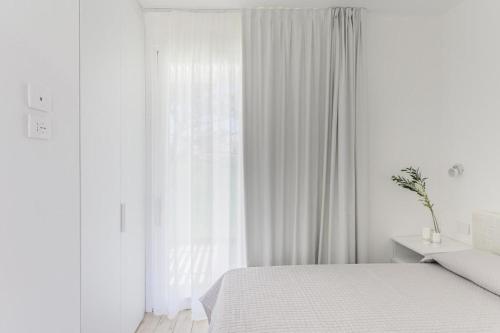 Una habitación blanca con una cama y una ventana en Stunning Capo Falcone Charming Apartments nm1359, en Stintino