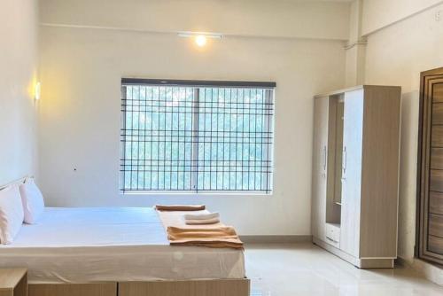 a white room with a bed and a window at Dazzle Mount Resort in Kalpetta