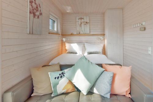 a room with two beds and a couch with pillows at Hausboot - Svanehus in Heiligenhafen