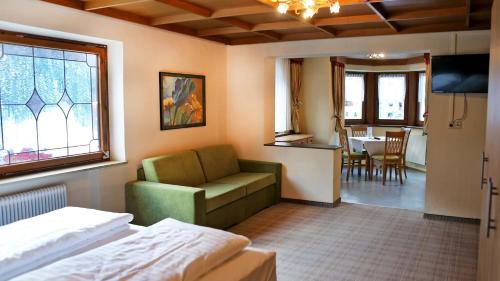 a hotel room with a bed and a couch and a table at Gasthof Pension Madseiterhof in Tux