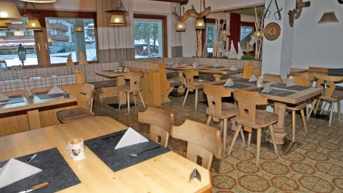 an empty restaurant with wooden tables and chairs at Gasthof Pension Madseiterhof in Tux
