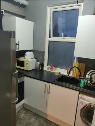 eine kleine Küche mit einem Waschbecken und einem Fenster in der Unterkunft Double room #1 in Hounslow