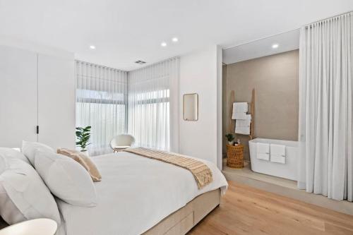 1 dormitorio blanco con 1 cama grande y baño en Iluka on the Avenue- 3 bedroom, 2 bathroom. Brand new. 150m walk to shops, en Ocean Grove