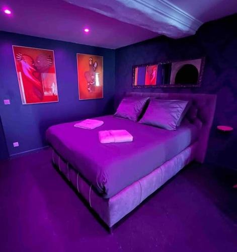 - une chambre violette avec un grand lit et un éclairage violet dans l'établissement Loveroom En Aparté Caen, à Caen