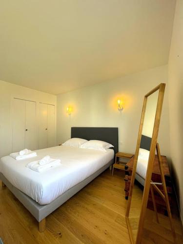 une chambre avec un grand lit blanc et un miroir dans l'établissement Appartement Port Le Pouliguen, au Pouliguen