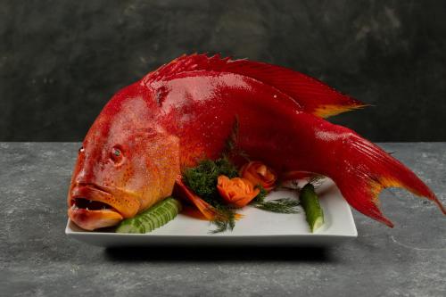a red fish sitting on a plate with vegetables at Villa Thamburu, Bentota in Bentota