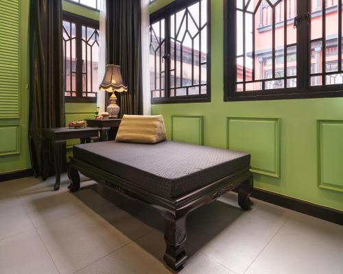 a bed in a room with green walls and windows at DE Phanakron Boutique Hotel in Bangkok