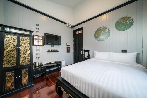 a bedroom with a bed and a tv on the wall at DE Phanakron Boutique Hotel in Bangkok