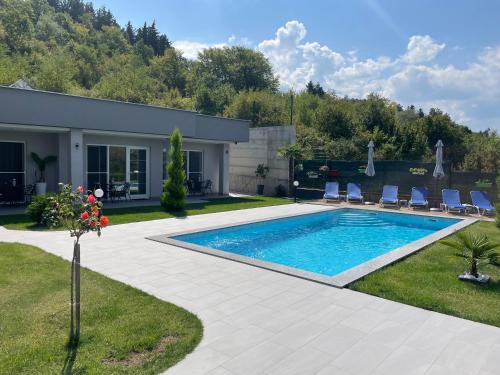 a swimming pool in a yard with chairs and a house at Villa Dimo Topal in Ohrid