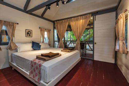 a bedroom with a large white bed and windows at SaffronStays Aquamarina in Nagaon