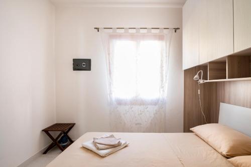 a white bedroom with a bed with a window at Casa Stellins in Santa Teresa Gallura